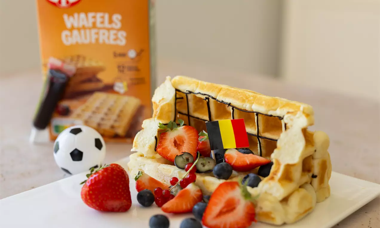 Gouden wafels gevormd als een voetbaldoel met zwart chocoladeraster, versierd met rode aardbeien, blauwe bessen en een Belgische vlag